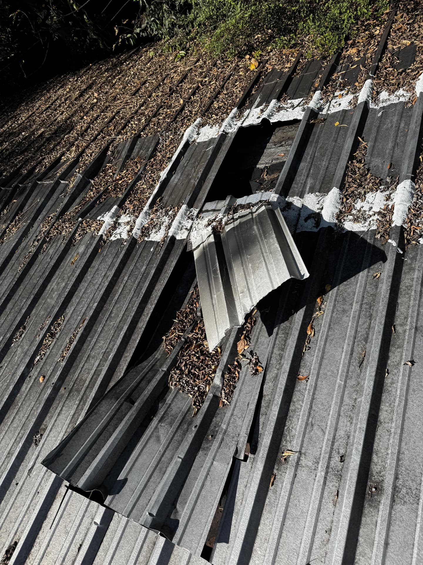 Close-up of torn and corroded metal roof panels before replacement